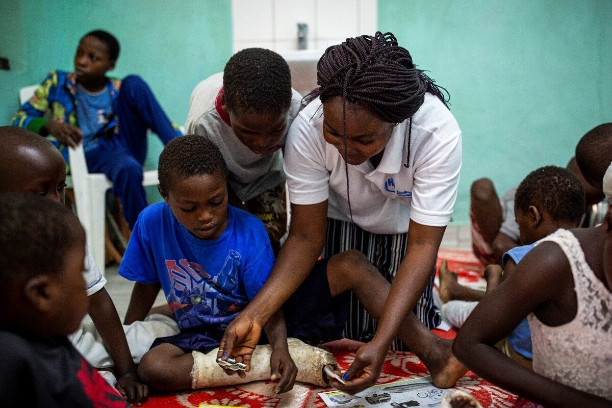 Séance de soutien psychosocial à l'hôpital de Rutshuru, au Nord Kivu, animée par Jonathan, le psychologue de HI. Kelvine et Kisubizo, deux petites filles amputées après avoir été blessées à la jambe (affrontements rebelles), participent activement. Sur la photo la psychologue Brigiete Omba. Photo: © Patrick Meinhardt / HI